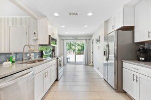 A modern kitchen with white cabinets, stainless steel appliances, and a tiled backsplash. - Beach House -optional BIKES - Walk 2 Shops & Fun (Saint Simons Island)