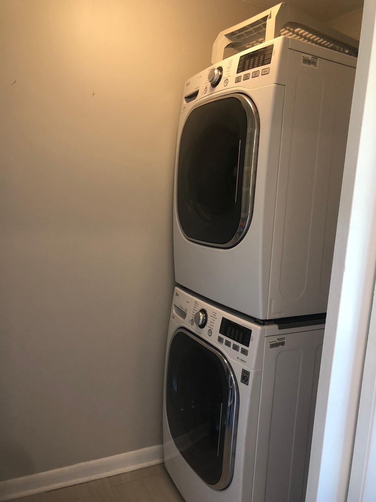 Eine gestapelte Waschmaschine und ein Trockner in einer Ecke neben einer schlichten Wand.