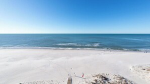 Una amplia playa de arena con cielo azul despejado y mar tranquilo.