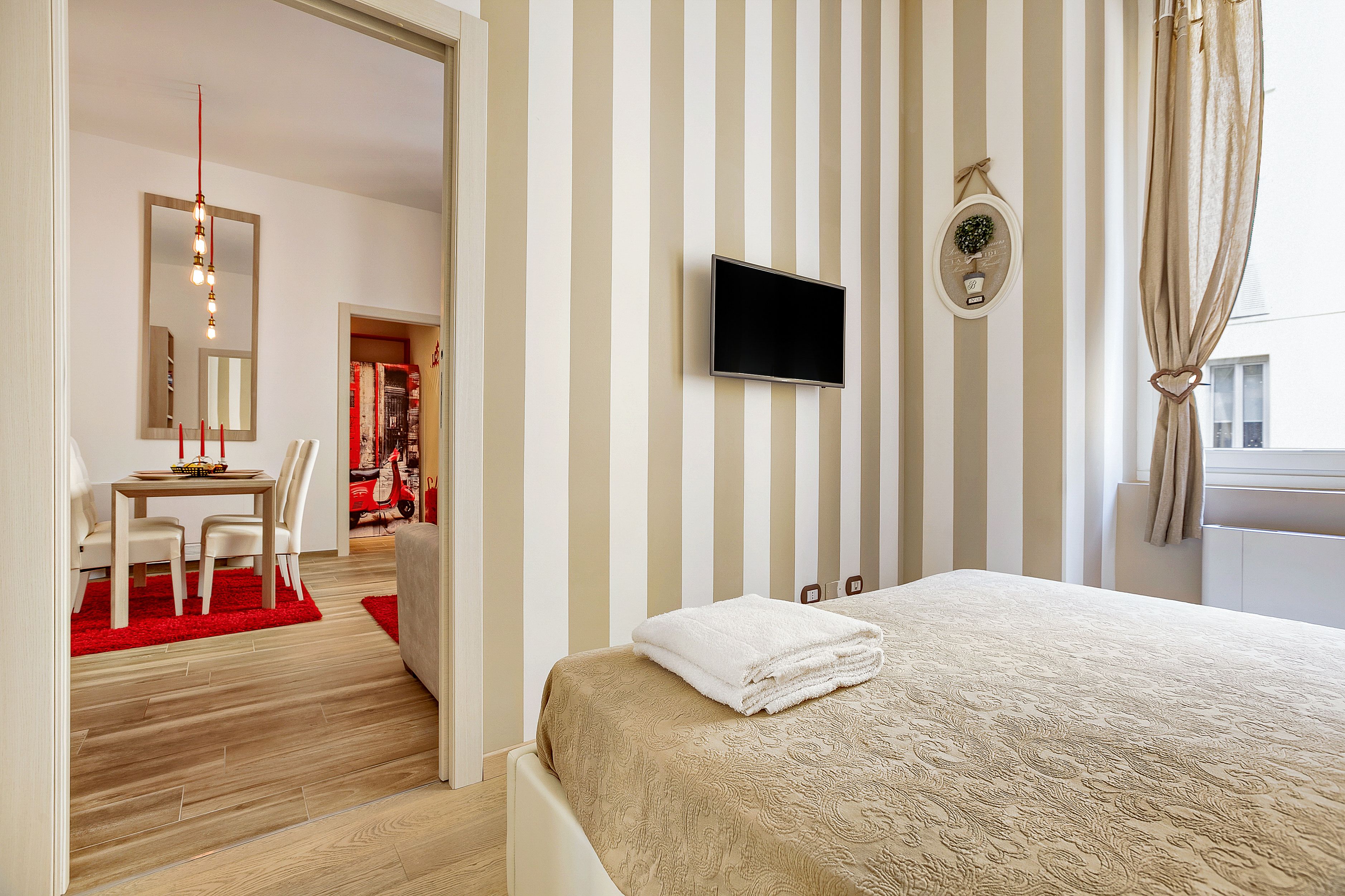 Ein Hotelzimmer mit Bett, Fernseher, Spiegel und Schreibtisch mit Stühlen.