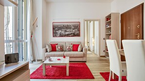 A modern living room with a sofa, coffee table, and red rug. - Vitruvio (Milan)