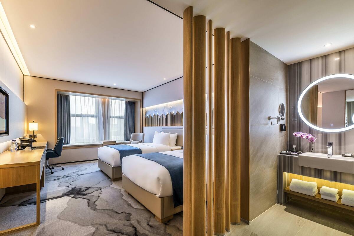 A hotel room with a bed, desk, and bathroom.