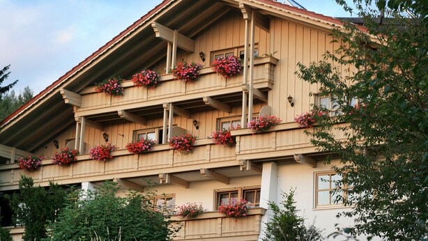 A multi-story building with balconies adorned with flower boxes. - Haus Vierjahreszeiten (Bodenmais)
