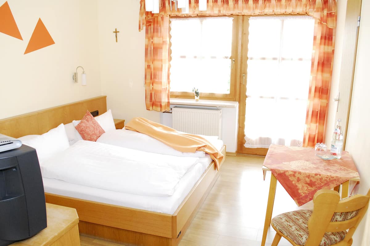 Ein Hotelzimmer mit einem Bett, einem Schreibtisch mit Stuhl, einem Heizkörper und Vorhängen.