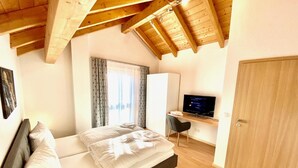 A bedroom with a bed, a desk, a TV, and a wardrobe. - Haus Vierjahreszeiten (Bodenmais)