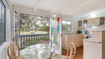 Enjoy a casual dining experience in this kitchen with an oven, microwave, and glass door leading to a balcony with a garden view.