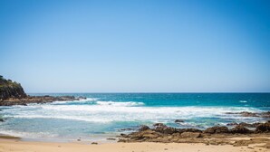 Ein Strand mit klarem, blauem Wasser, felsigem Ufer und einem Sandstrand.
