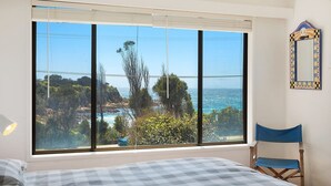Ein Schlafzimmer mit einem großen Fenster und Blick auf Strand und Meer.