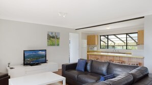 Ein modernes Wohnzimmer mit Ledersofa, Flachbildfernseher und weißem Couchtisch.