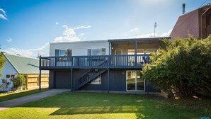 A two-story house with a balcony, a garage, and a well-maintained lawn. - House One @ Potato Point (POTATO POINT)