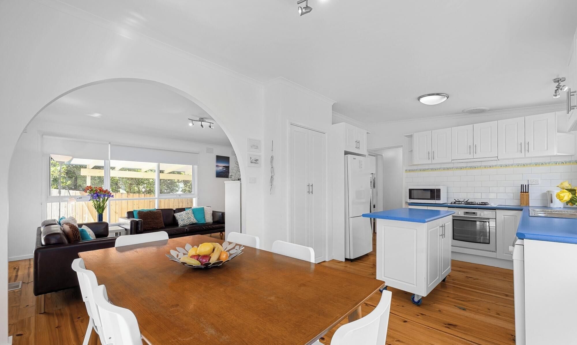 A modern kitchen with white cabinets, a blue countertop, and a central island.