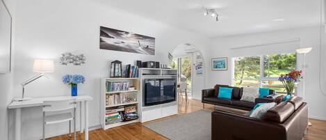 A modern living room with a fireplace, a sofa, a coffee table, and a bookshelf.