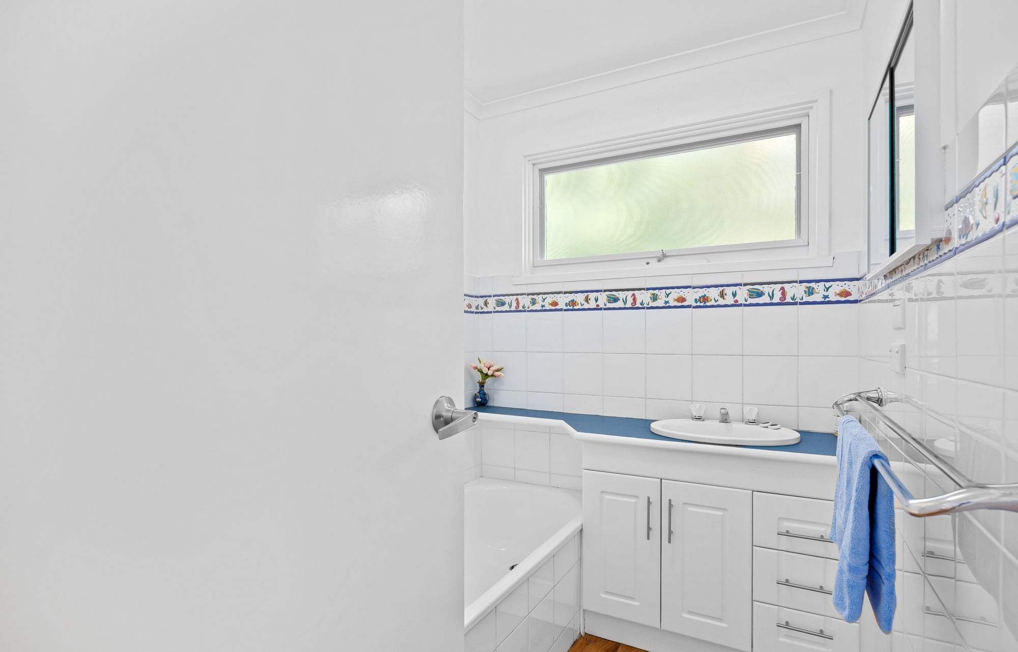 Un baño con bañera, ventana y lavabo.