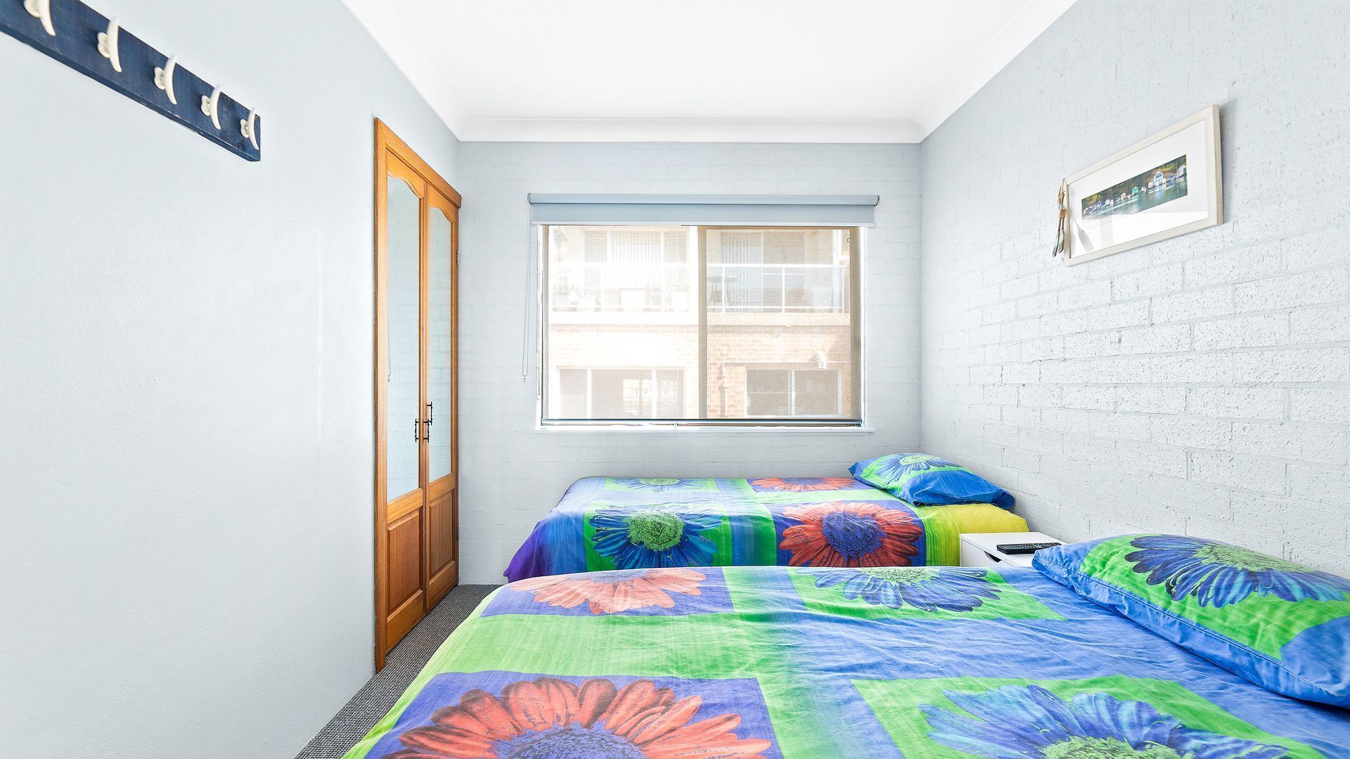 Una habitación pequeña y luminosa con dos camas, una ventana y una puerta.