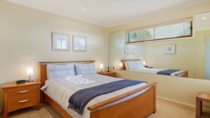 A bedroom with a wooden bed, bedside tables, a mirror, and framed pictures on the wall.