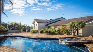 Un jardin arrière aménagé, avec une piscine, un jacuzzi et un espace clos agrémenté de différentes plantes.