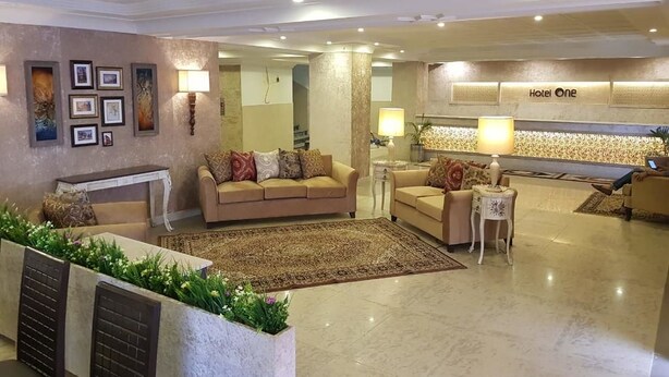A hotel lobby with a beige sofa set, a patterned rug, and a reception desk. - Hotel One Mall Road Murree (Murree)