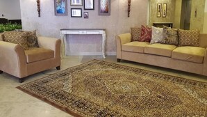 A living room with two sofas, a patterned rug, wall-mounted lamps, and framed artwork. - Hotel One Mall Road Murree (Murree)