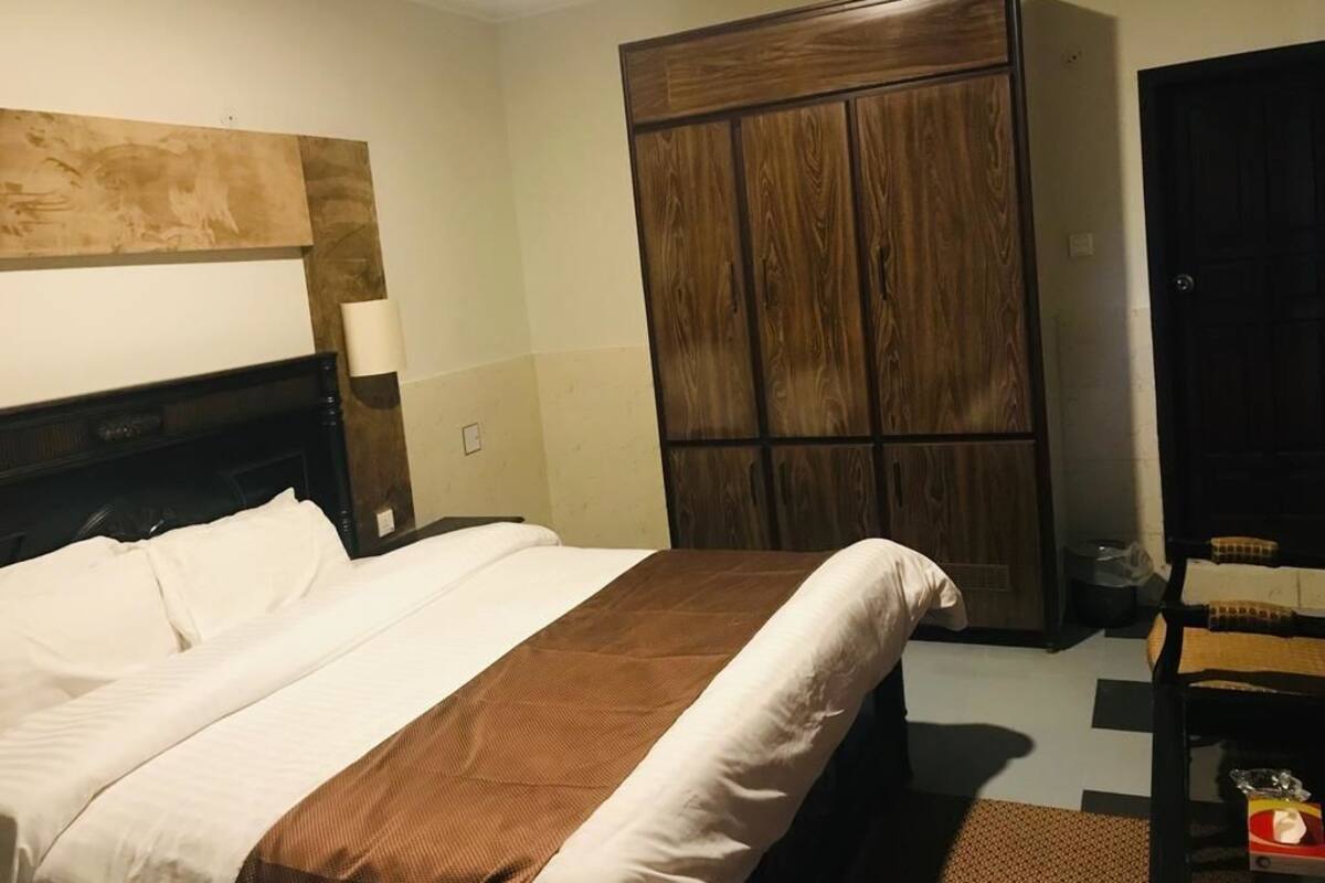 A hotel room with a large bed, a wardrobe, and a desk with a chair.