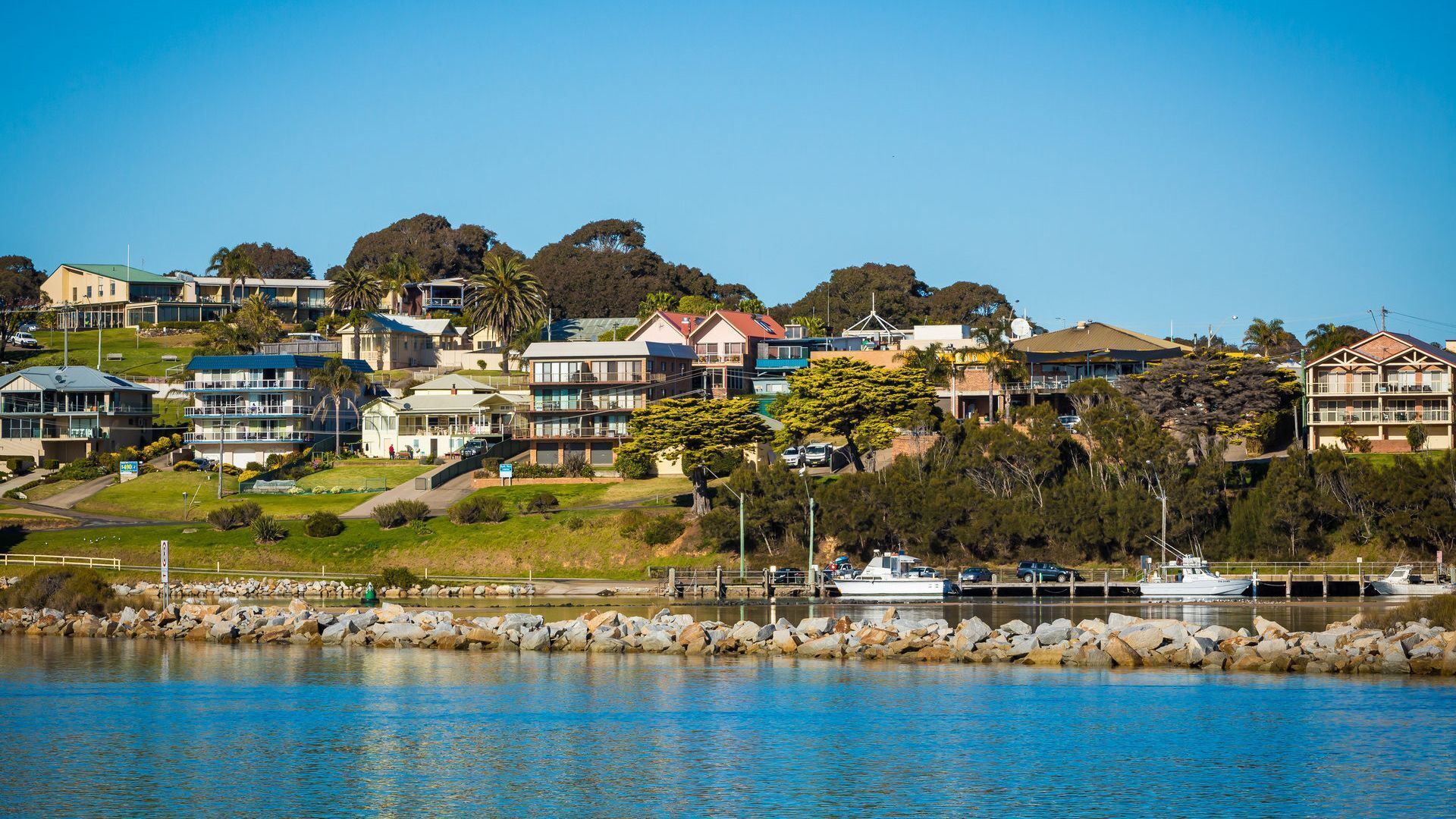 A coastal residential area with houses, a marina, and a rocky shoreline.