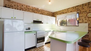 Een compacte keuken met witte kasten, een inbouwoven, een magnetron en een groen aanrecht.
