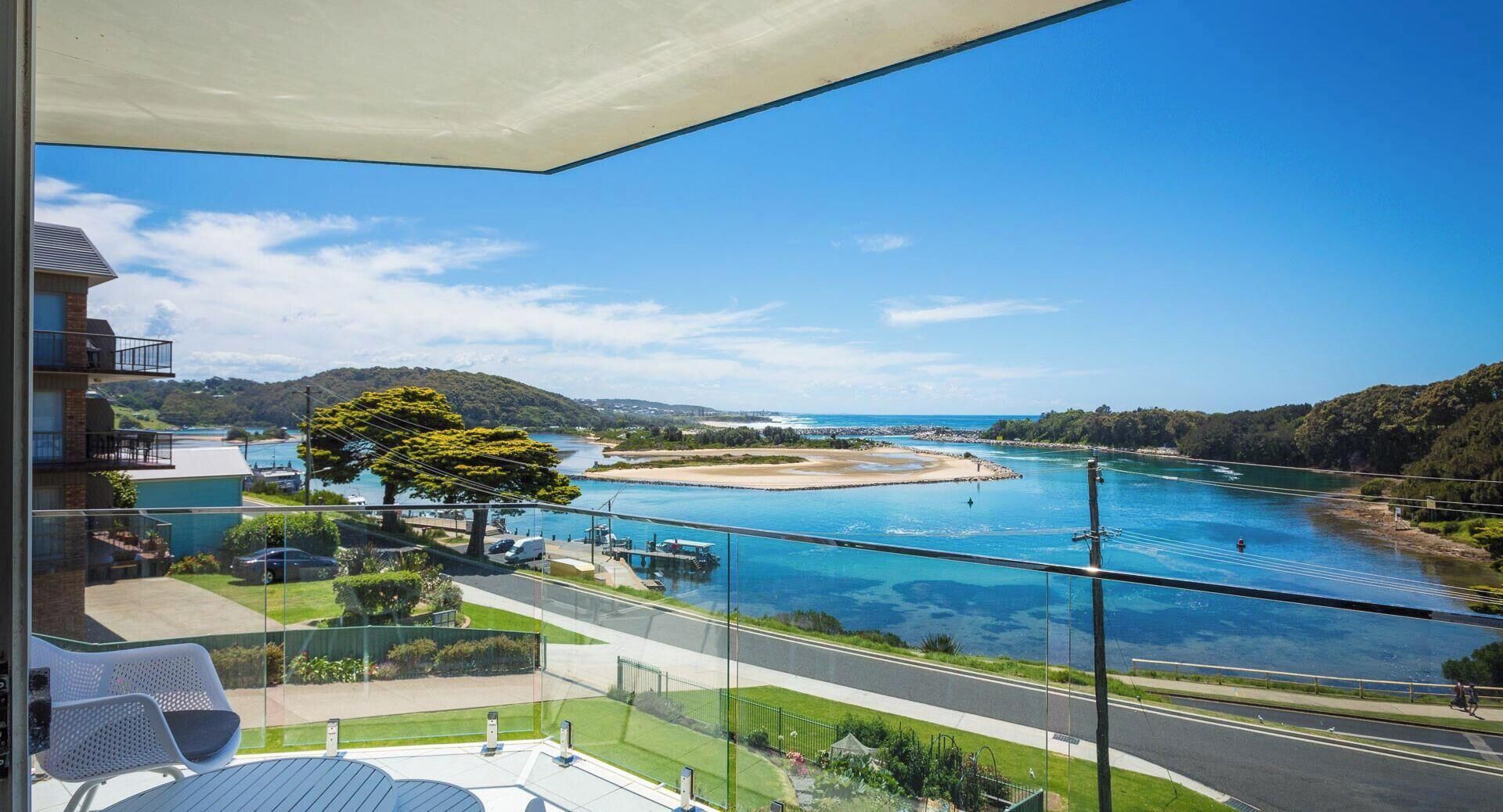 Un balcon offrant une vue dégagée sur une rivière, une plage et un paysage vallonné.