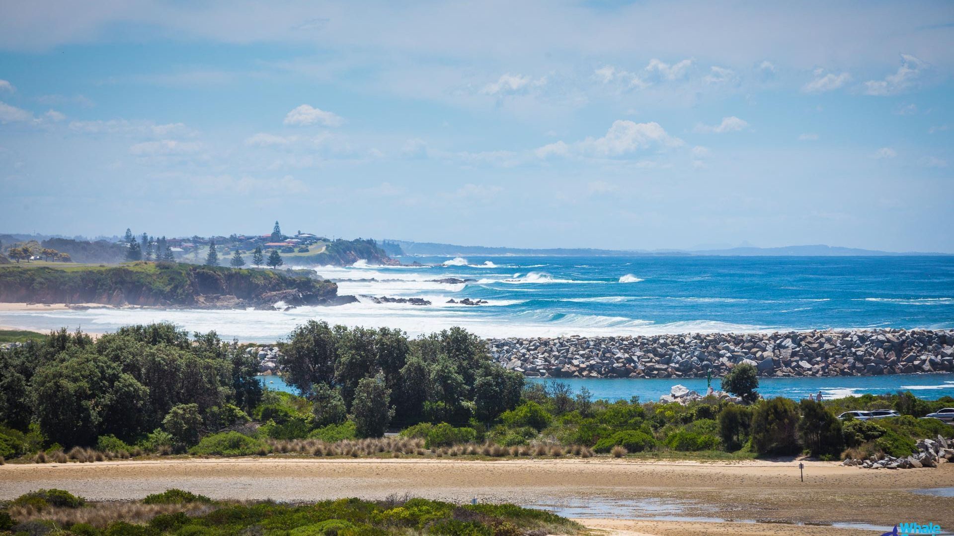 A coastal landscape with a rocky shoreline, a sandy beach, and a view of the ocean.