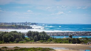 A coastal landscape with a rocky shoreline, a sandy beach, and a view of the ocean.