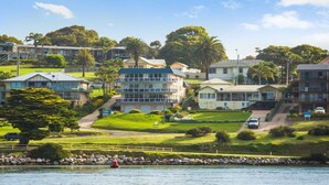 A coastal residential area with houses, a clear view of the sea, and a rocky shoreline.