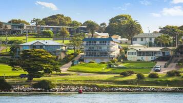 A coastal residential area with houses, a clear view of the sea, and a rocky shoreline.