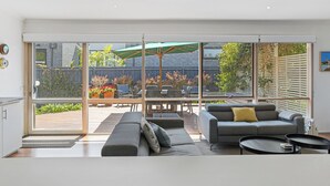 A modern living room with a large sliding glass door leading to an outdoor patio area.