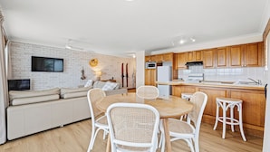 A modern apartment with a living room, dining area, and kitchen. - Grand Pacific 1 Unit 1 - Ground Floor (NAROOMA)