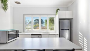 Eine moderne Küche mit einer großen Kochinsel, einer eingebauten Mikrowelle und einem Edelstahl-Kühlschrank.