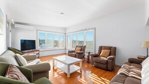 Ein Wohnzimmer mit Fernseher, zwei Sofas, einem Couchtisch und einer Lampe.