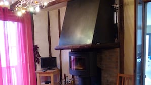 A living room with a fireplace, a sofa, and a television on a stand. - Chambres d'hôtes Las Vignes (Beaucens)