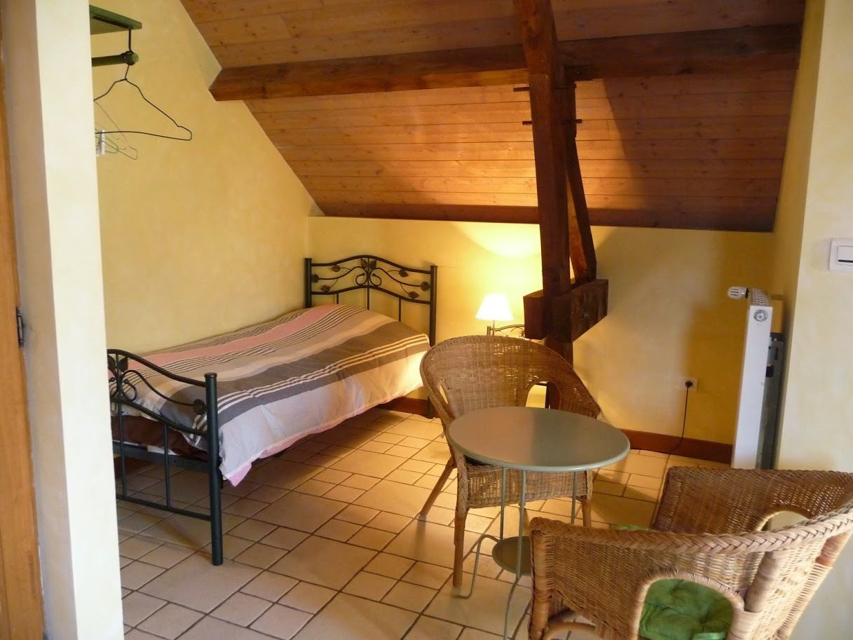 Una habitación pequeña con cama, una mesa y sillas de mimbre.