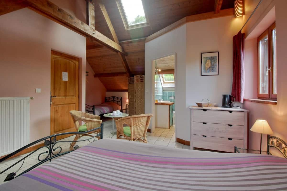 Un dormitorio acogedor con cama, sillas de mimbre, cómoda y vista a la cocina.