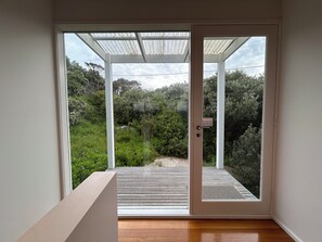 A room with a sliding glass door leading to an outdoor deck. - BASS | 13 GUEST | TENNIS COURT | VIEWS | PORTSEA GOLF CLUB | LOCATION (Portsea)