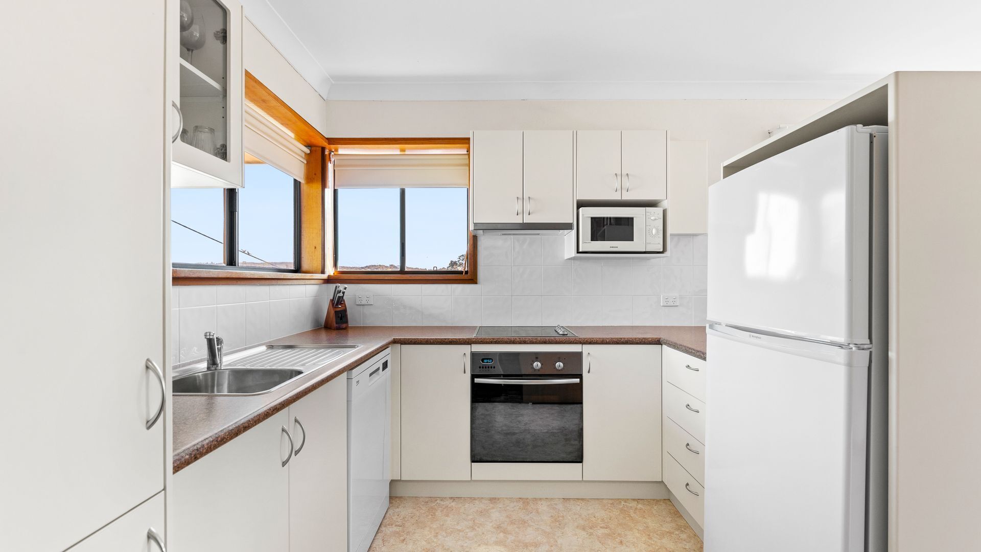 A compact kitchen with white cabinets, a microwave, a dishwasher, and a sink.