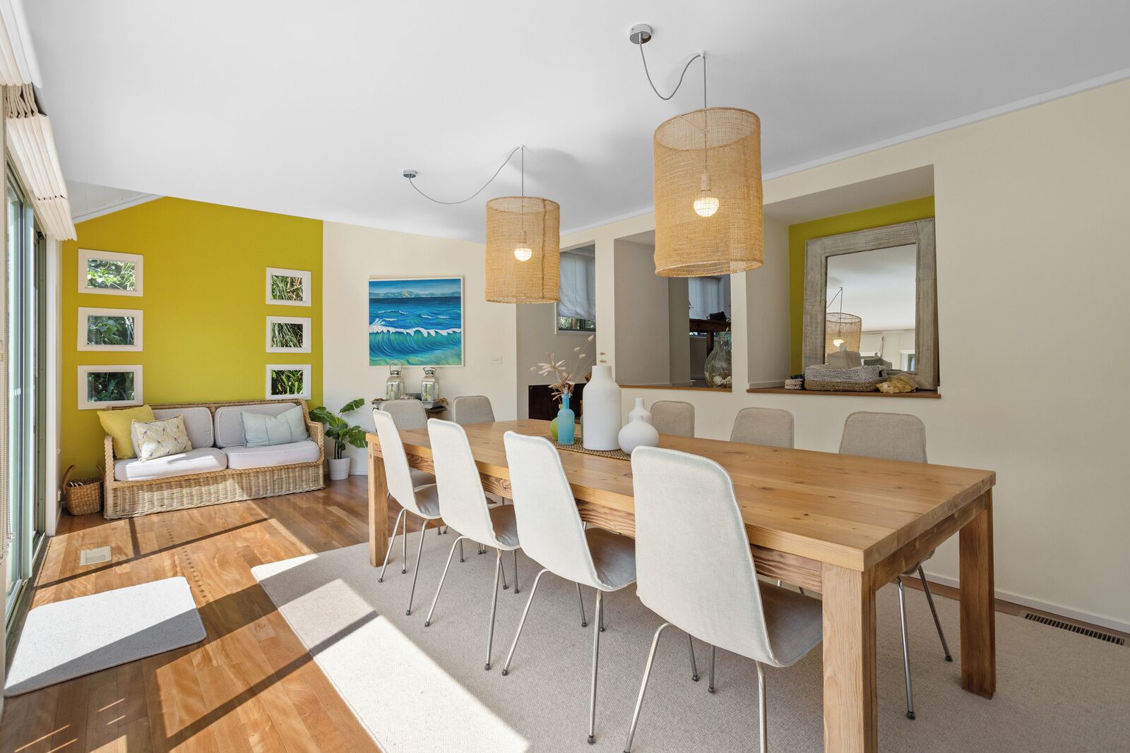 Un comedor con una mesa de madera, sillas blancas y una lámpara colgante.