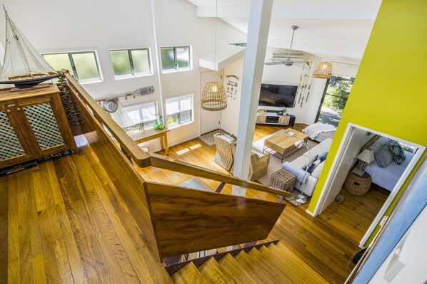 A spacious living area with a wooden staircase, a television, and a dining area. - CAPTIVATING CENTENARY BEACH HOUSE IN BLAIRGOWRIE (Blairgowrie)
