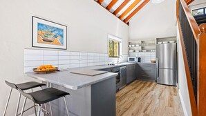 A modern kitchen with a marble countertop, stainless steel appliances, and a wooden ceiling. - Bush Retreat With Private Pool (NAROOMA)