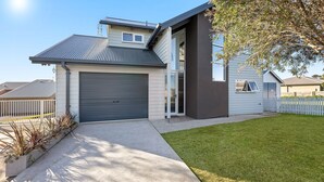 Ett modernt hus i två våningar med garage, en täckt uteplats och en välskött gräsmatta.