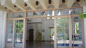 Un interior amplio con techo alto, ventanas grandes y una escalera que sube a un nivel superior.