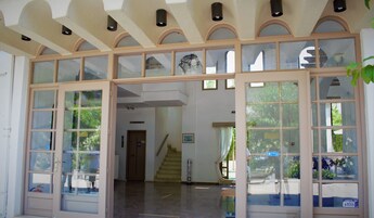 Un interior amplio con techo alto, ventanas grandes y una escalera que sube a un nivel superior.