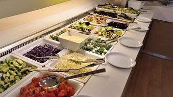 Un bufé con diversas opciones de comida, incluyendo ensaladas, verduras y carnes.