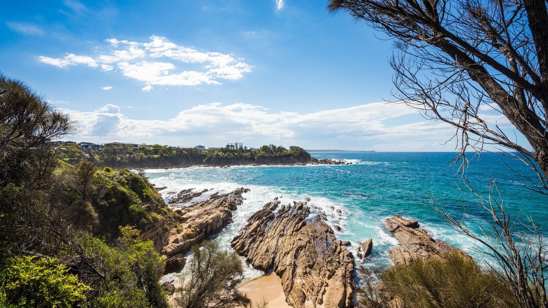 Paisaje costero con terreno rocoso, una playa y vista al océano.