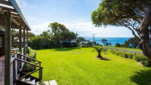 A grassy area with a wooden deck, a tree, and a view of the ocean.
