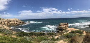 Un paisaje costero con acantilados rocosos, una playa de arena y el océano.