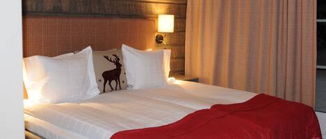 Ein Hotelzimmer mit Bett, einer roten Decke, einer Lampe und einem Vorhang.